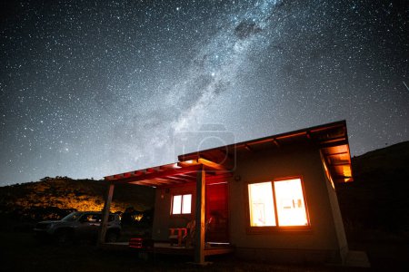 Photo for Starry sky and little house glowing red in the mountains - Royalty Free Image