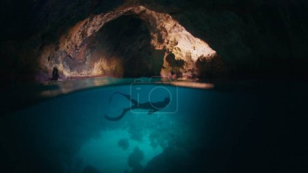 Foto de Freediver nada bajo el agua en la cueva. Hombre libre explora la cueva y nadar bajo el agua dentro de ella - Imagen libre de derechos