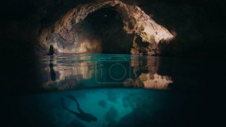 Photo for Freediver swims underwater in the cave. Male freediver explores the cave and swimming underwater inside it - Royalty Free Image