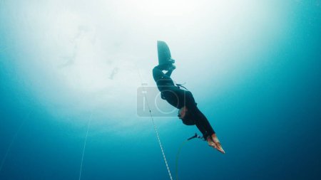 Foto de Libre sobre la cuerda en un mar. Hombre libre desciende a lo largo de la cuerda en monofín - Imagen libre de derechos