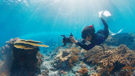 Foto de Fotógrafo submarino toma fotos del arrecife de coral saludable. Freediver con cámara nada sobre el arrecife. Nusa Penida, Bali, Indonesia - Imagen libre de derechos