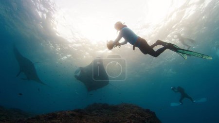Foto de El fotógrafo submarino toma fotos de manta ray. Freediver con películas de cámara Océano gigante Manta Ray nadando sobre el arrecife. Nusa Penida, Bali, Indonesia - Imagen libre de derechos
