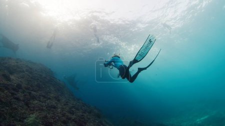 Foto de El fotógrafo submarino toma fotos de manta ray. Freediver con películas de cámara Océano gigante Manta Ray nadando sobre el arrecife. Nusa Penida, Bali, Indonesia - Imagen libre de derechos