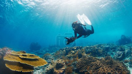 Foto de Fotógrafo submarino toma fotos del arrecife de coral saludable. Freediver con cámara nada sobre el arrecife. Nusa Penida, Bali, Indonesia - Imagen libre de derechos