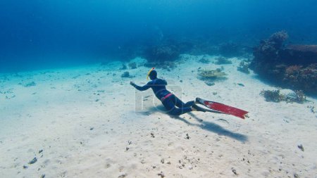 Foto de Hombre freediver se desliza en el mar tropical sobre el fondo arenoso - Imagen libre de derechos