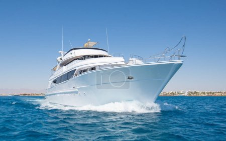 Téléchargez les photos : Un yacht à moteur privé de luxe en cours sur la mer tropicale avec une vague d'arc - en image libre de droit