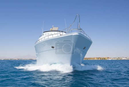Téléchargez les photos : Un yacht à moteur privé de luxe en cours sur la mer tropicale avec une vague d'arc - en image libre de droit