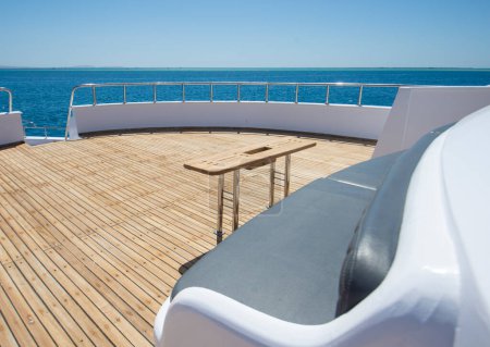 Téléchargez les photos : Pont d'étrave en teck d'un grand yacht à moteur de luxe avec chaises canapé table et fond vue sur la mer tropicale - en image libre de droit