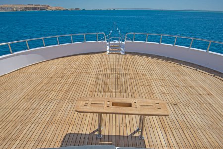 Téléchargez les photos : Pont d'étrave en teck d'un grand yacht à moteur de luxe avec table en bois et fond vue sur la mer tropicale - en image libre de droit
