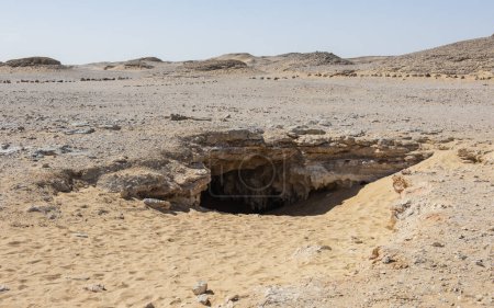 Foto de Paisaje vista panorámica del desierto desolado occidental estéril en Egipto con vista rocosa y entrada a la cueva subterránea de Djarra - Imagen libre de derechos