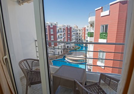 Téléchargez les photos : Meubles de terrasse d'un appartement de luxe dans une station tropicale avec mobilier et vue sur la piscine depuis le balcon - en image libre de droit