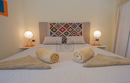 Téléchargez les photos : Décoration d'intérieur ameublement de luxe montrer maison chambre à coucher montrant gros plan de meubles et lit double avec serviettes - en image libre de droit