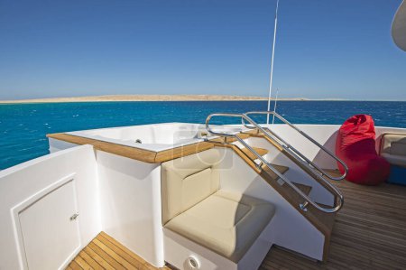 Teak bow wooden deck of a large luxury motor yacht with hot tub and tropical sea view background