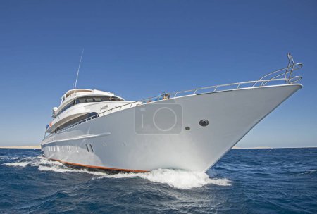 Téléchargez les photos : Un grand yacht à moteur privé de luxe en cours de navigation sur la mer tropicale avec une vague d'arc - en image libre de droit