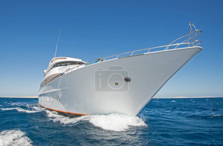 Téléchargez les photos : Un grand yacht à moteur privé de luxe en cours de navigation sur la mer tropicale avec une vague d'arc - en image libre de droit