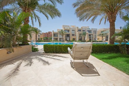 Téléchargez les photos : Terrasse patio jardin d'un appartement de luxe dans un complexe tropical avec mobilier et vue sur la piscine - en image libre de droit