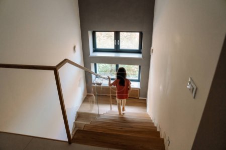 Téléchargez les photos : Brunette girl wearing home clothes going down stairs at home - en image libre de droit