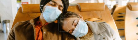 Téléchargez les photos : Couple indien portant des masques pour le visage dormant assis à l'aéroport à l'intérieur - en image libre de droit