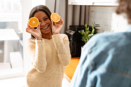 Foto de Chica negra haciendo mientras hace jugo de naranja con su madre en la cocina en casa - Imagen libre de derechos