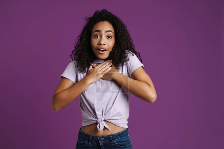 Téléchargez les photos : Jeune femme noire gesticulant tout en exprimant sa surprise devant la caméra isolée sur fond violet - en image libre de droit