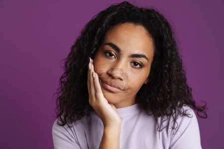 Photo for Young black woman propping up her head and looking at camera isolated over purple background - Royalty Free Image