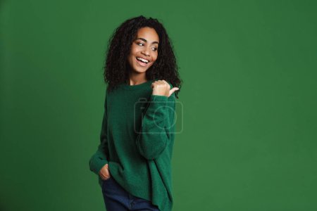 Téléchargez les photos : Jeune femme noire riant tout en pointant du doigt isolé sur fond vert - en image libre de droit