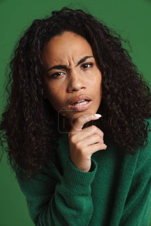 Photo for Young black woman frowning and looking at camera isolated over green background - Royalty Free Image
