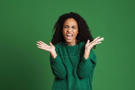 Photo for Young black woman with wavy hair screaming while gesturing isolated over green background - Royalty Free Image