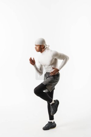 Téléchargez les photos : Jeune sportif portant bandana faire de l'exercice tout en travaillant isolé sur fond blanc - en image libre de droit