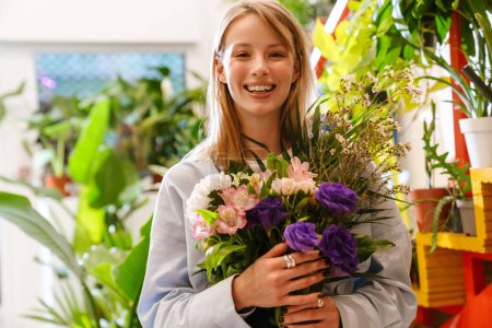 Photo for White beautiful young florist girl holding bouquet with fresh flowers in shop - Royalty Free Image