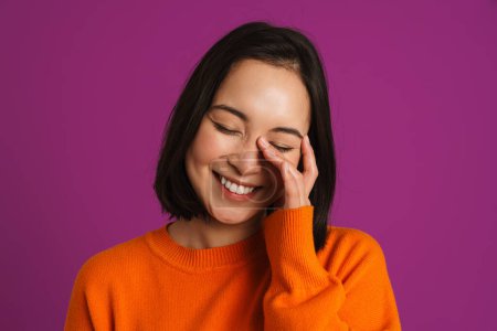 Téléchargez les photos : Jeune femme asiatique riant et couvrant son visage isolé sur fond violet - en image libre de droit