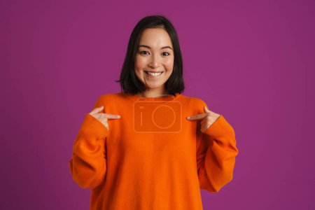 Photo for Young asian woman smiling and pointing fingers at herself isolated over purple background - Royalty Free Image