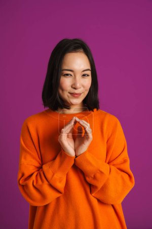 Photo for Young asian woman gesturing while smiling at camera isolated over purple background - Royalty Free Image