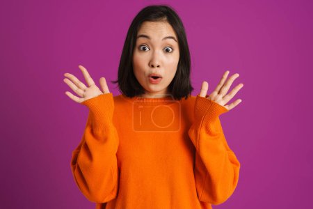 Téléchargez les photos : Jeune femme asiatique geste tout en exprimant surprise à la caméra isolé sur fond violet - en image libre de droit