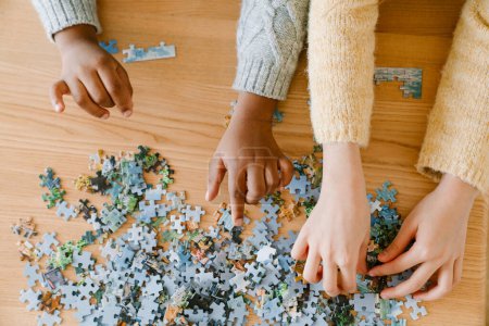 Top view of interracial childrens hands solving puzzles