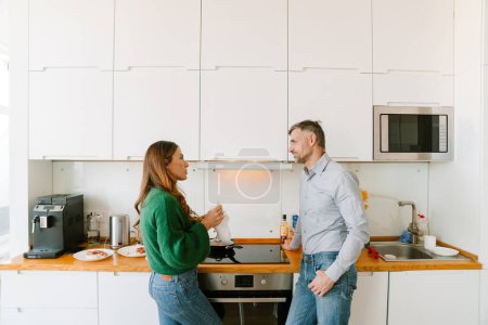 Téléchargez les photos : Homme déçu regardant sa femme dans la cuisine debout près du poêle - en image libre de droit