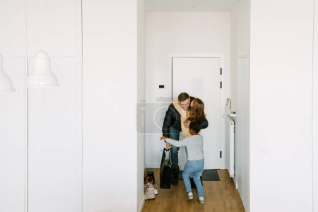 Téléchargez les photos : Heureuses sœurs adoptives rencontrant à la porte le père qui est rentré à la maison - en image libre de droit