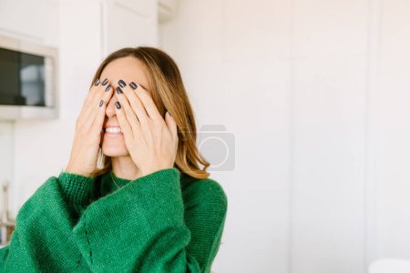 Téléchargez les photos : Femme souriante couvrant ses yeux avec ses mains tout en jouant à cache-cache - en image libre de droit