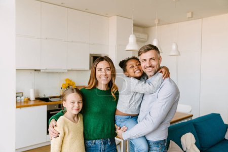 Photo for Happy family on cozy kitchen at home. Father, mother and two daughters. Adoption concept - Royalty Free Image