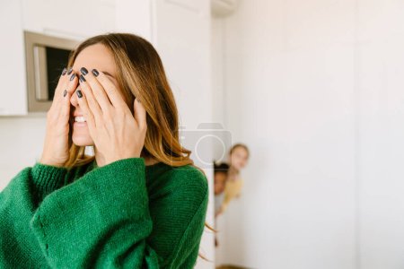Photo for Mother covering her eyes with her hands while playing hide-and-seek with her daughters. Adoption concept - Royalty Free Image