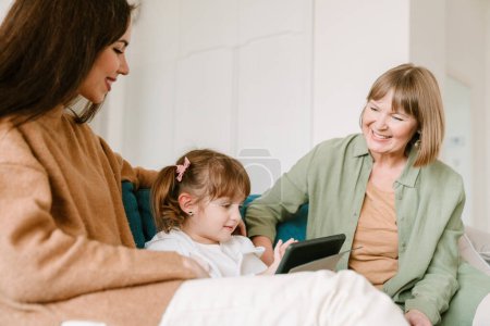 Foto de Chica blanca usando tableta mientras pasa tiempo con su familia en casa - Imagen libre de derechos