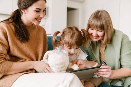 Foto de Chica blanca usando tableta mientras pasa tiempo con su familia en casa - Imagen libre de derechos
