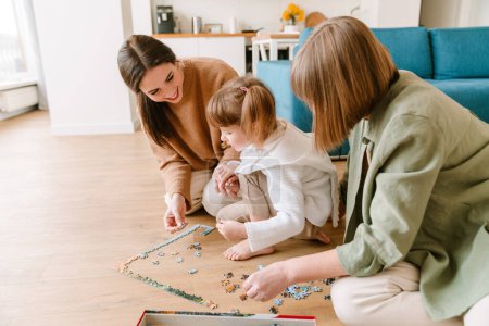Téléchargez les photos : Blanc fille blonde compléter puzzle avec sa famille à la maison - en image libre de droit