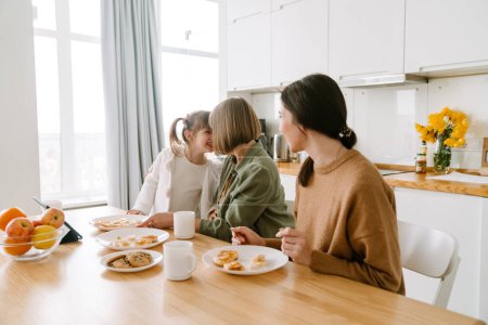 Téléchargez les photos : Famille blanche prendre le petit déjeuner tout en passant du temps ensemble à la maison - en image libre de droit
