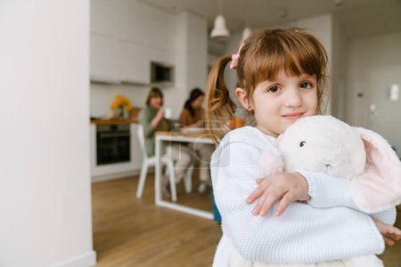 Photo for White girl smiling and holding toy while spending time with her family at home - Royalty Free Image