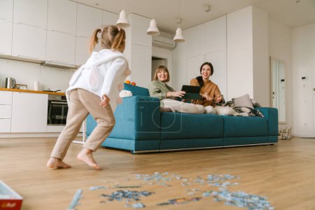 Foto de Chica rubia blanca completando rompecabezas mientras pasa tiempo con su familia en casa - Imagen libre de derechos
