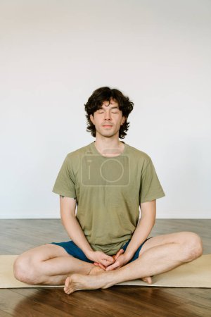Téléchargez les photos : Homme blanc portant un short méditant pendant la pratique du yoga à la maison - en image libre de droit