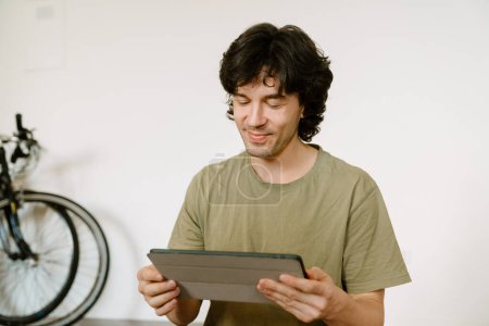 Foto de Hombre blanco sonriendo y usando la tableta mientras pasa tiempo en casa - Imagen libre de derechos