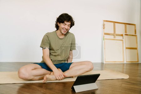 Photo for White man using tablet computer during yoga practice at home - Royalty Free Image