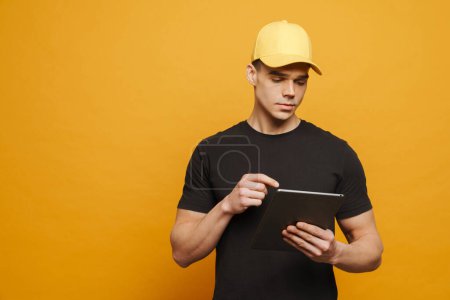 Photo for Young white man wearing cap typing while using tablet computer isolated over yellow background - Royalty Free Image